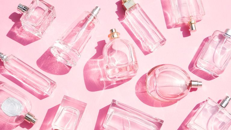 flatlay di bottiglie di profumo su sfondo rosa