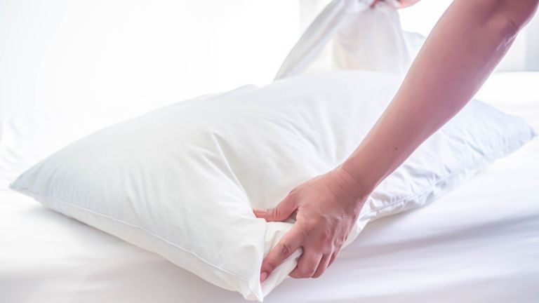 Almofada branca na cama no quarto com mulher