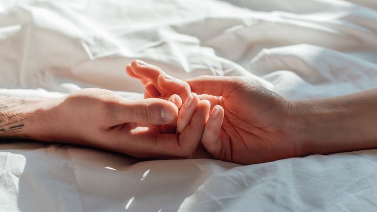 Paar Händchen haltend im Bett