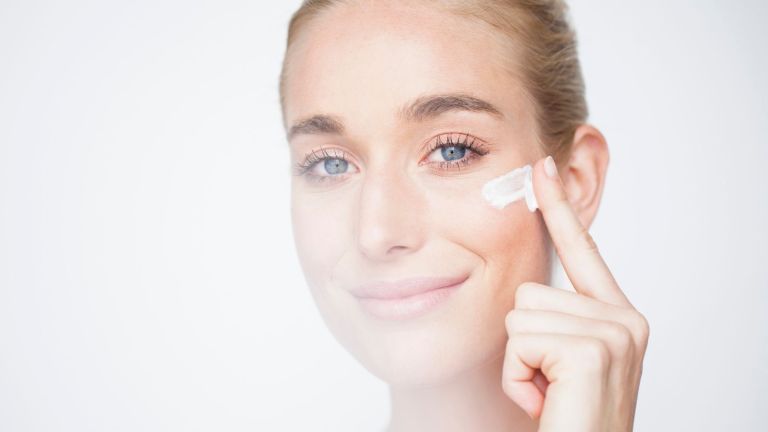 como usar retinol imagem principal de mulher com pés de galinha aplicando creme no rosto
