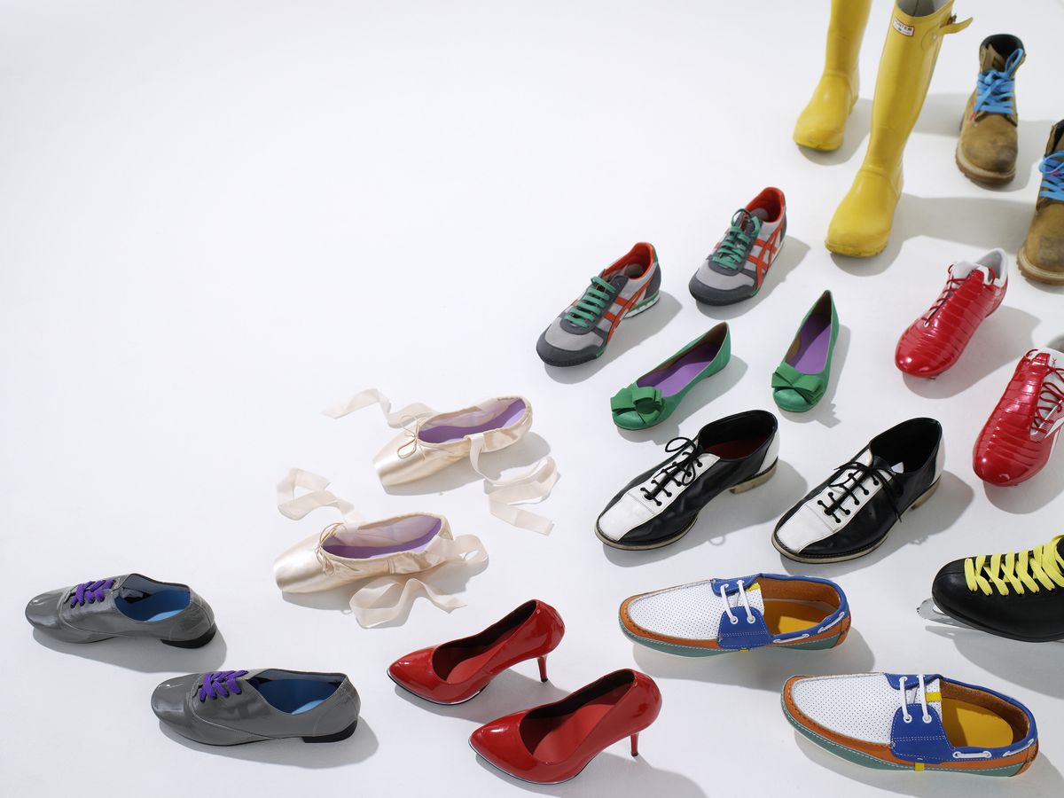 Muitos sapatos coloridos dispostos em um padrão de caminho em um fundo branco