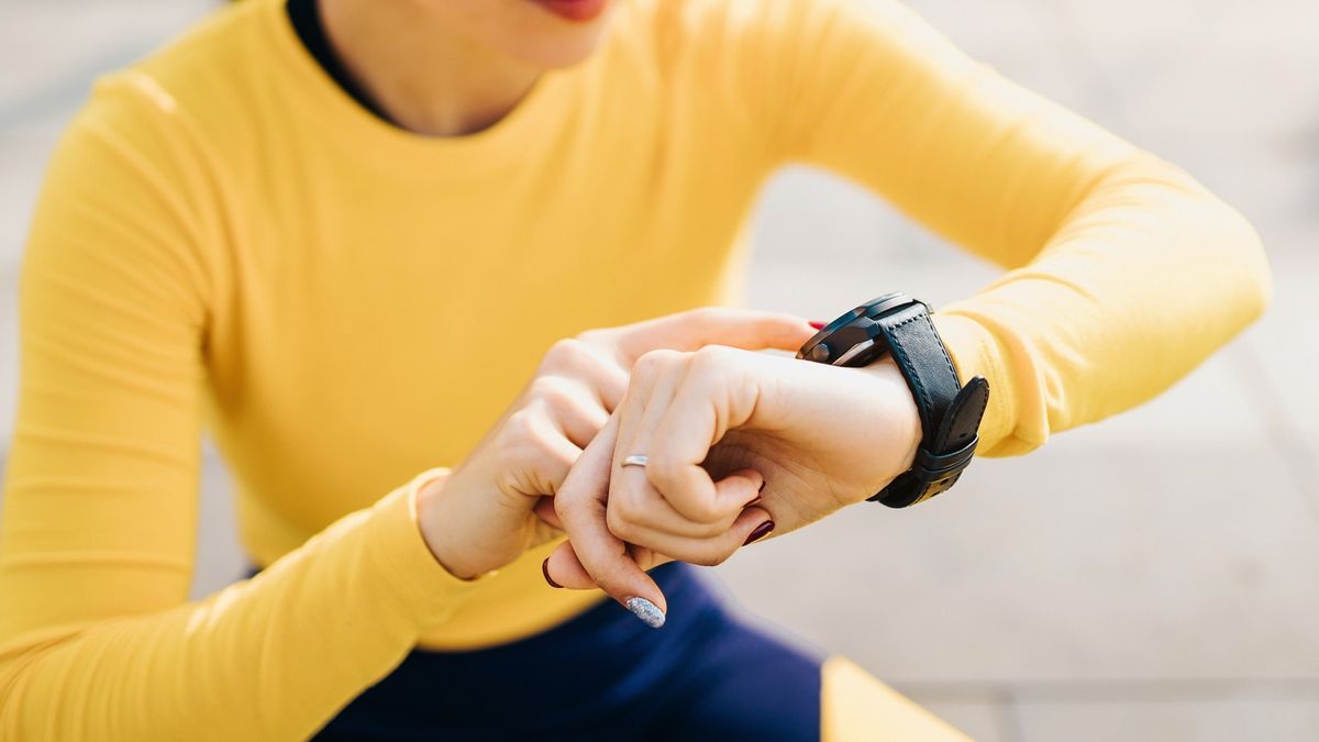 Wie lange sollten Laufschuhe halten: Frau checkt Fitnessuhr