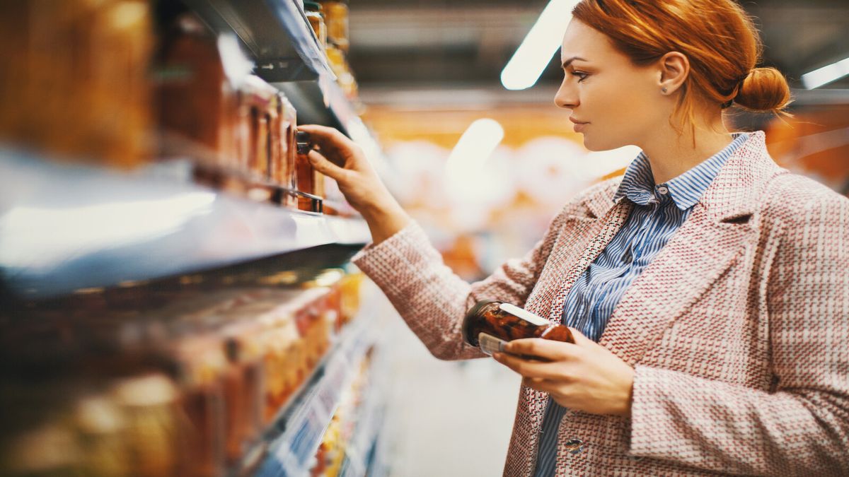 Mujer comprobando la etiqueta de los alimentos del supermercado dieta sin azúcar