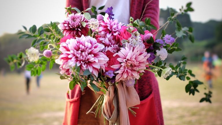 Mulher segurando um buquê de flores cor de rosa