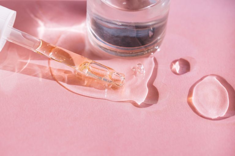 Produktaufnahme von Medizinpipette mit Glycerin auf rosa Hintergrund