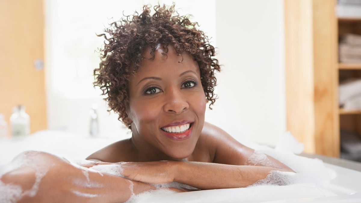 por que tomar banho todos os dias é ruim, mulher afro-americana relaxando em um banho de espuma
