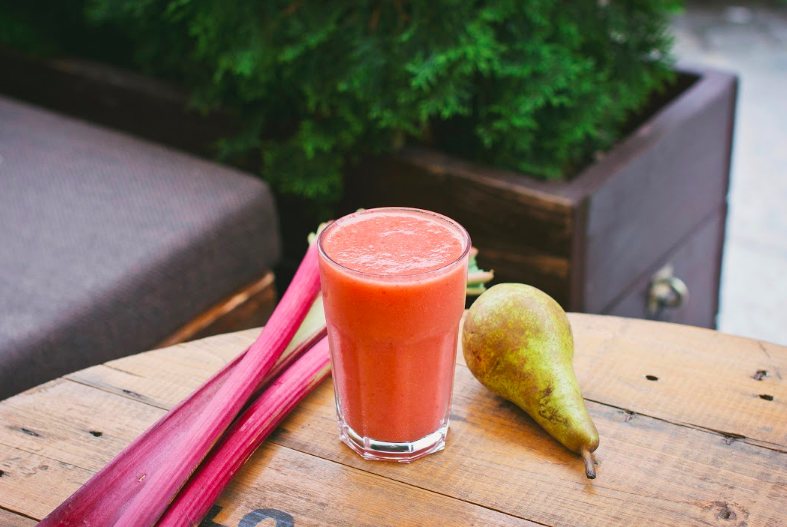 Smoothie z hrušky a rebarbory ​​v pohári na stole s rebarborou a hruškou vedľa nápoja