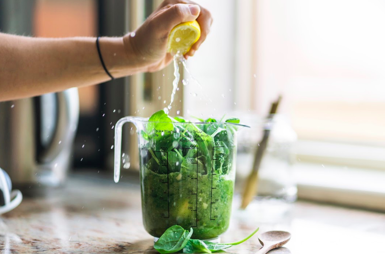 Ingrediencie pre konečný recept zeleného smoothie sa dajú do džbánu s ručným stláčaním citrónu do džbánu