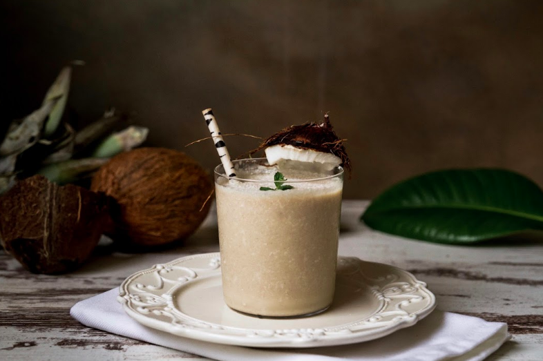 Čerstvé kokosové a ananásové smoothie v pohári s papierovou slamkou