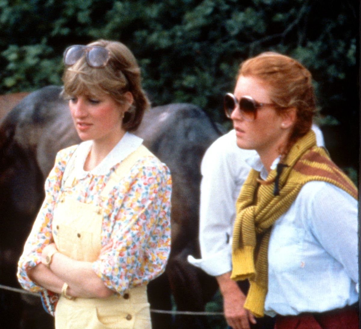 Lady Diana Spencer, vestida con un peto amarillo con una blusa floral y cuñas rojas, y Sarah Ferguson asisten a un partido de polo en el Cowdray Park Polo Club en Gloucestershire, el 12 de julio de 1981 (Foto de Anwar Hussein / Getty Images).