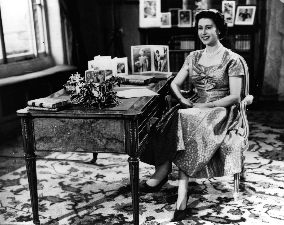 25 декември 1957 г.: Кралица Елизабет II се усмихва на принц Филип, херцог на Единбург точно преди края на първата си телевизионна реч за Коледа пред своята нация