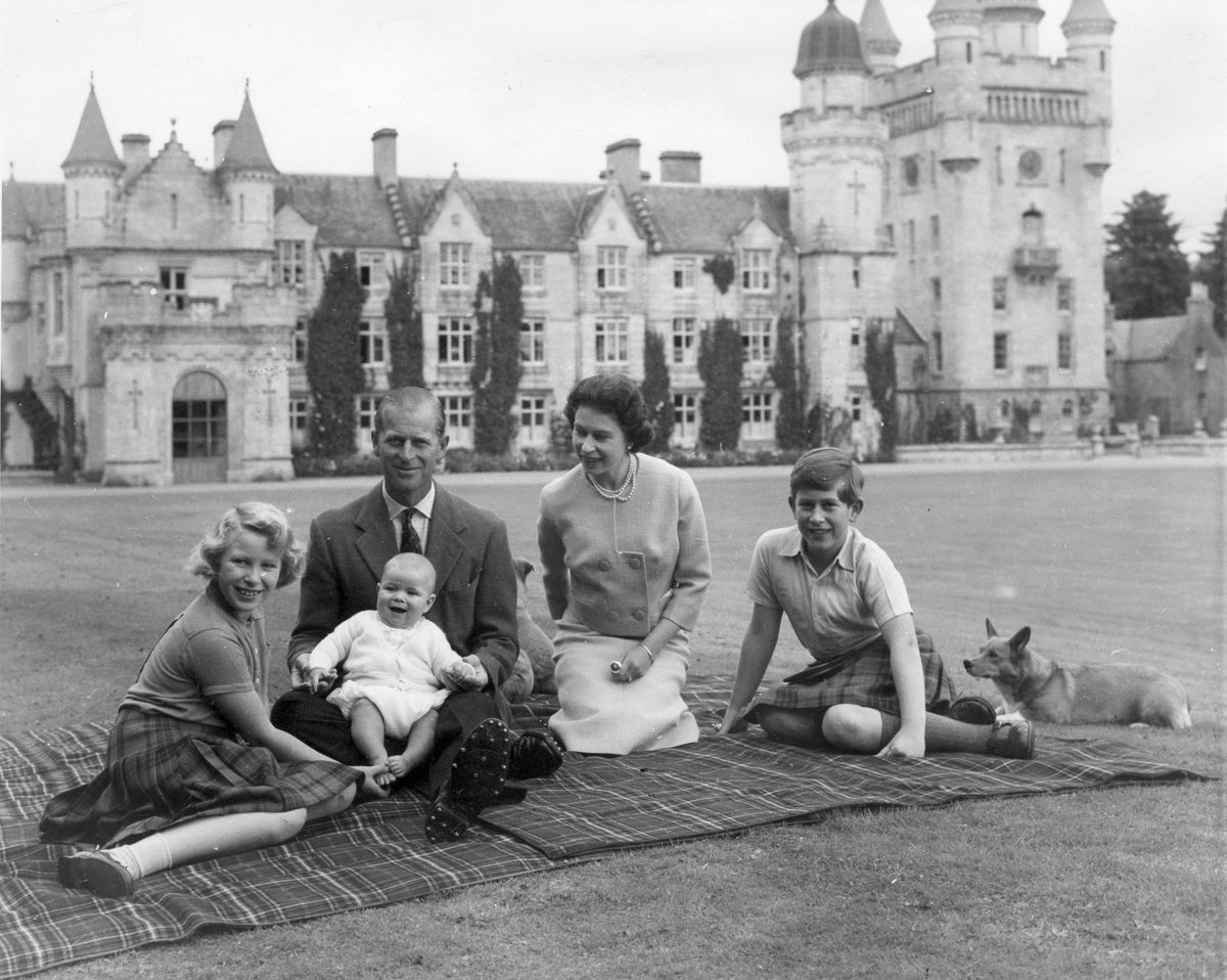 La regina Elisabetta II e il principe Filippo, duca di Edimburgo con i loro figli, il principe Andrea (al centro), la principessa Anna (a sinistra) e Carlo, principe di Galles, seduti su un tappeto da picnic fuori dal castello di Balmoral in Scozia
