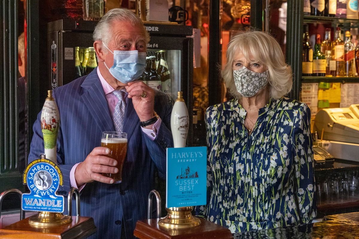 CLAPHAM, INGHILTERRA - 27 MAGGIO: Il principe Carlo, principe di Galles tira una pinta di birra in un pub insieme a Camilla, duchessa di Cornovaglia durante una visita alla città vecchia di Clapham il 27 maggio 2021 a Clapham, in Inghilterra. (Foto di Heathcliff O