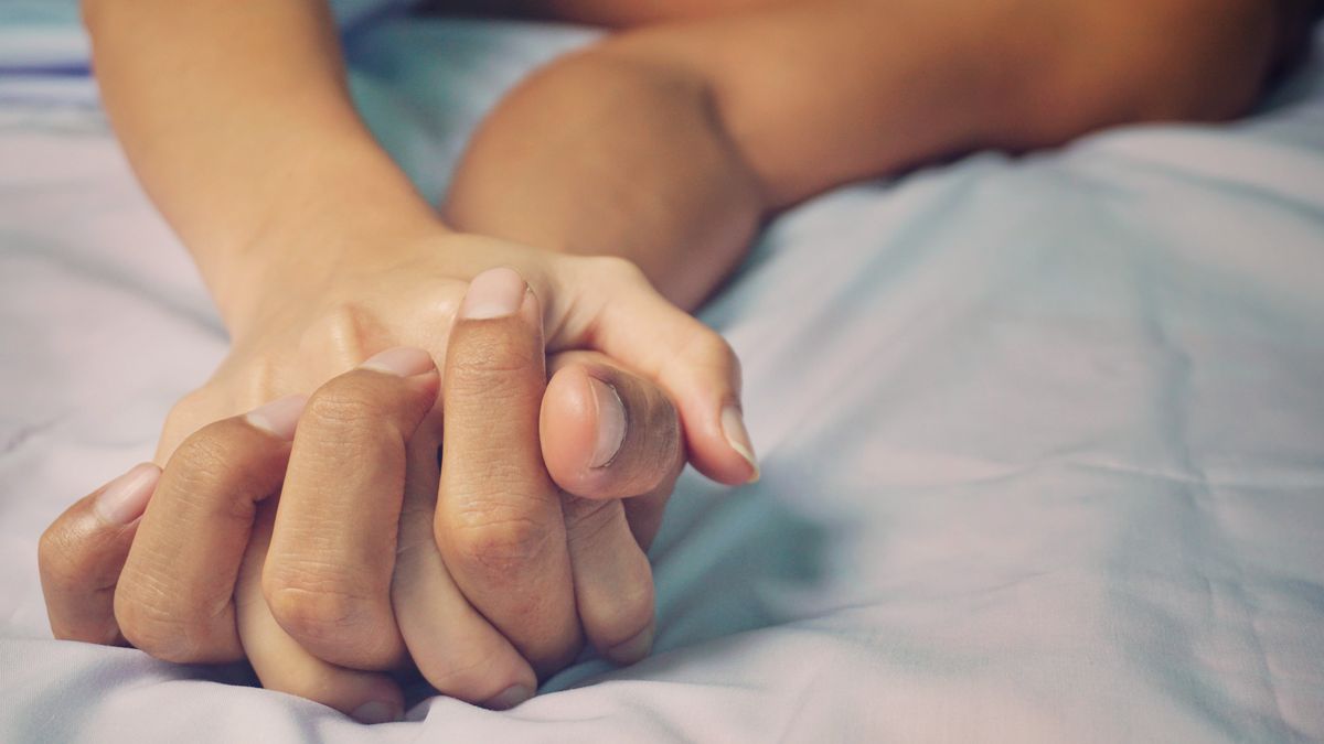 Paar Händchen haltend im Bett