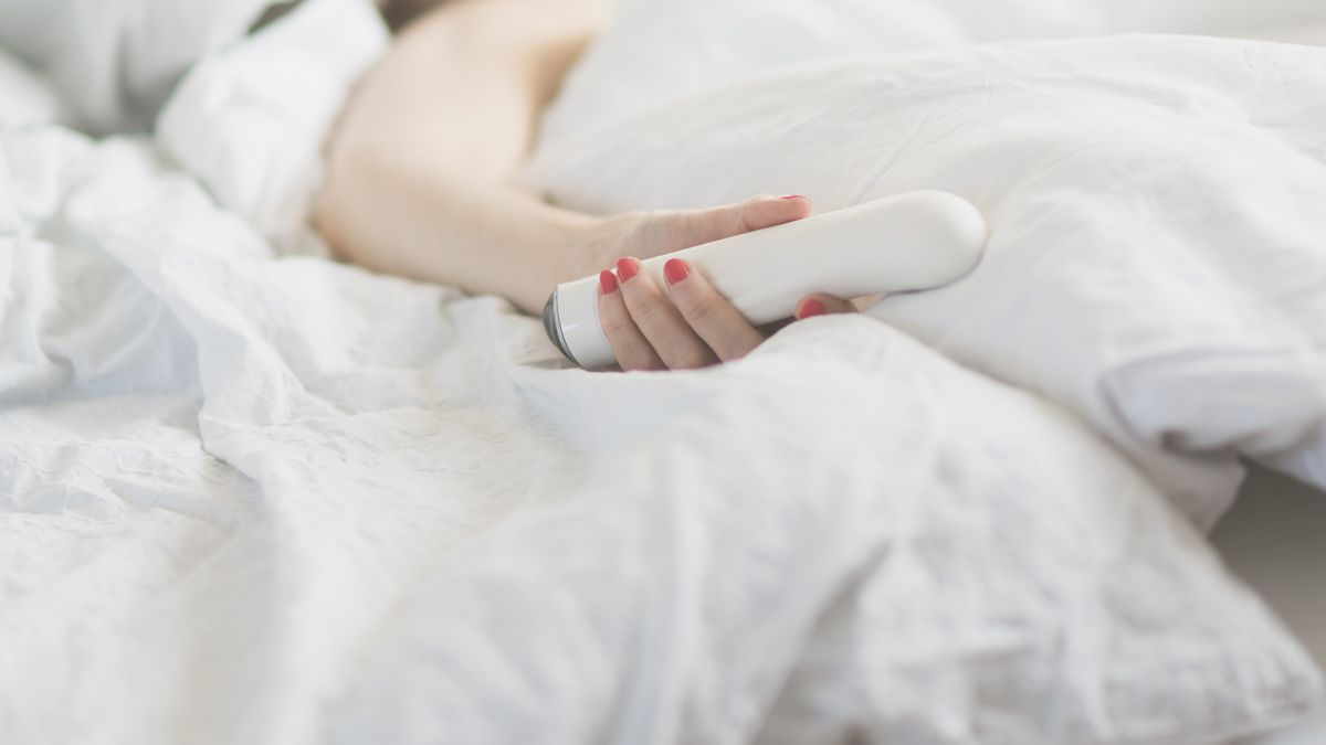 Frau mit Vibrator im Bett