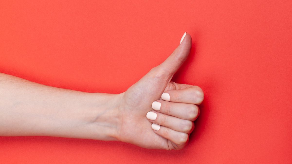 Frau Daumen hoch auf orangem Hintergrund