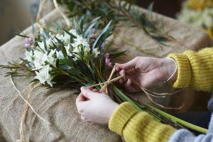 Floristería femenina haciendo ramo de flores de cerca como regalos de agradecimiento.